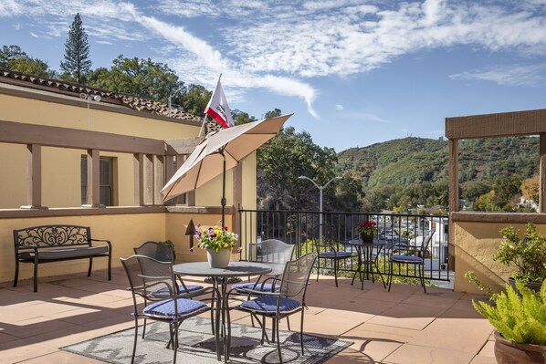 Une terrasse extérieure avec une table et des chaises, un drapeau et une vue sur le paysage environnant.