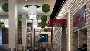 A hotel lobby with a modern design, including a sign for the Hilton Garden Inn, a staircase, and decorative green spheres. - Homewood Suites by Hilton Atlanta Midtown, GA (Atlanta)