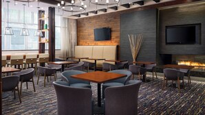 A modern hotel lobby with a fireplace, seating area, and multiple tables and chairs. - Homewood Suites by Hilton Atlanta Midtown, GA (Atlanta)