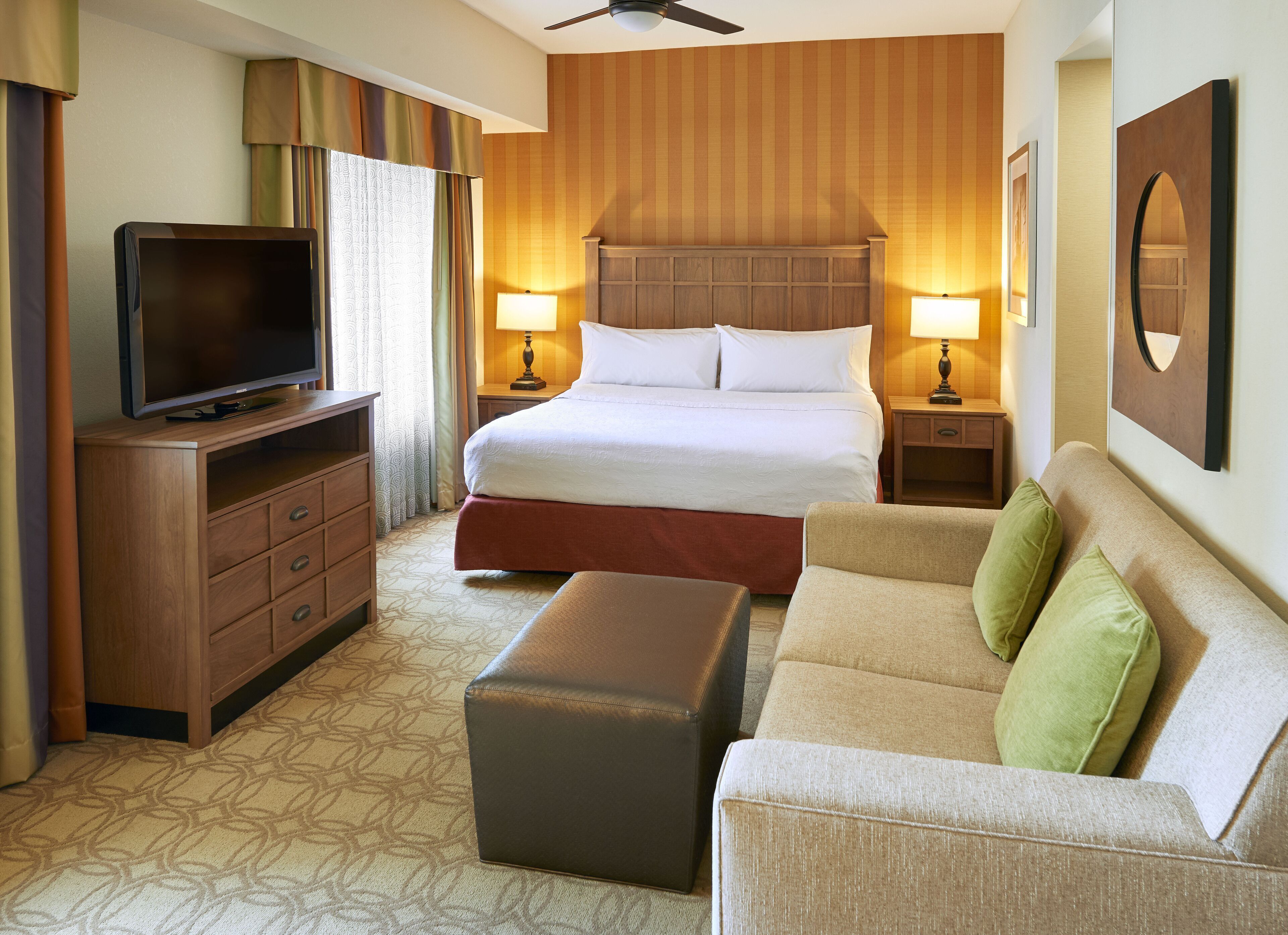 Une chambre d’hôtel équipée d’un lit, d’une télévision, d’un canapé, d’un bureau et d’un ventilateur de plafond.
