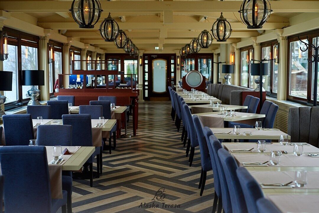 Un restaurante con un amplio espacio central para comer, varias mesas y sillas.