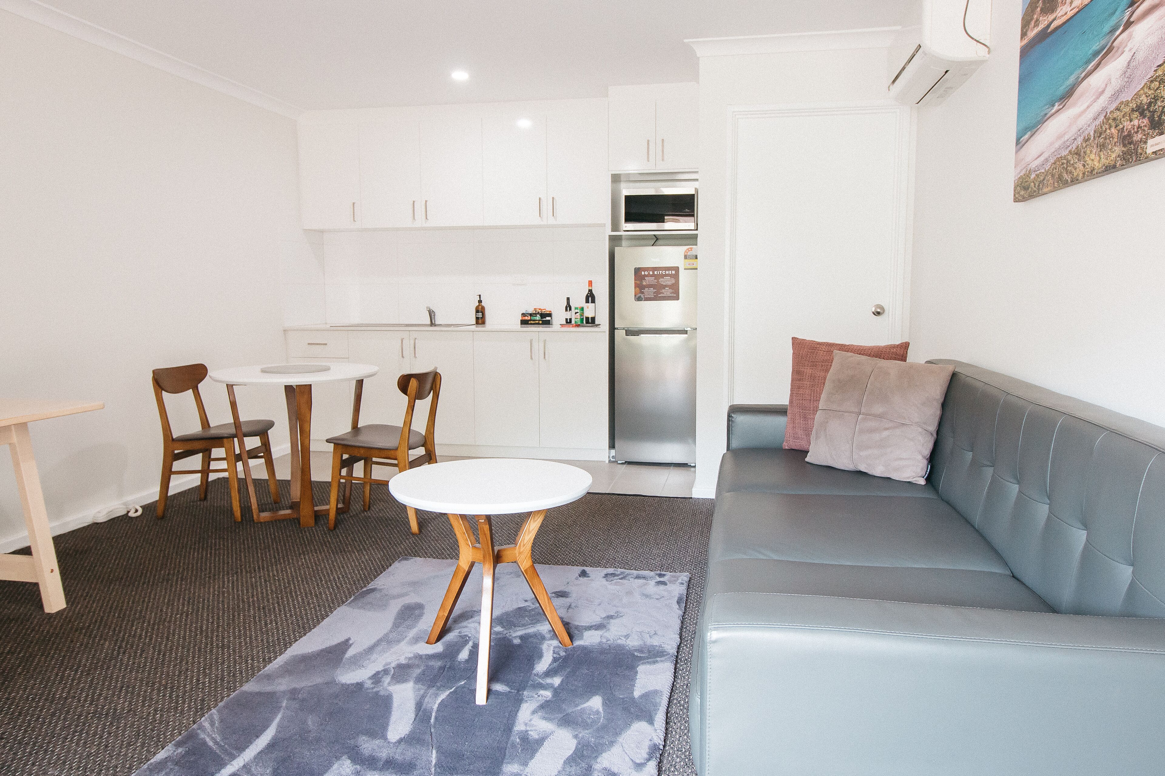 A compact living space with a kitchenette, a dining area with a table and chairs, and a seating area with a sofa and a rug.