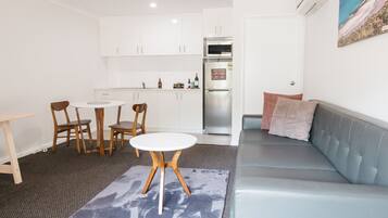 A compact living space with a kitchenette, a dining area with a table and chairs, and a seating area with a sofa and a rug.