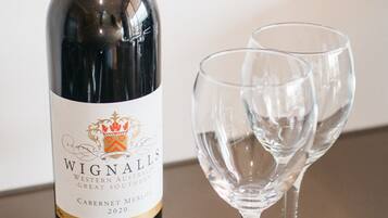 A bottle of Wignall's Cabernet Merlot 2020 next to two empty wine glasses on a table.