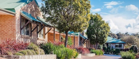 A brick building with a covered walkway and a tree in the foreground.