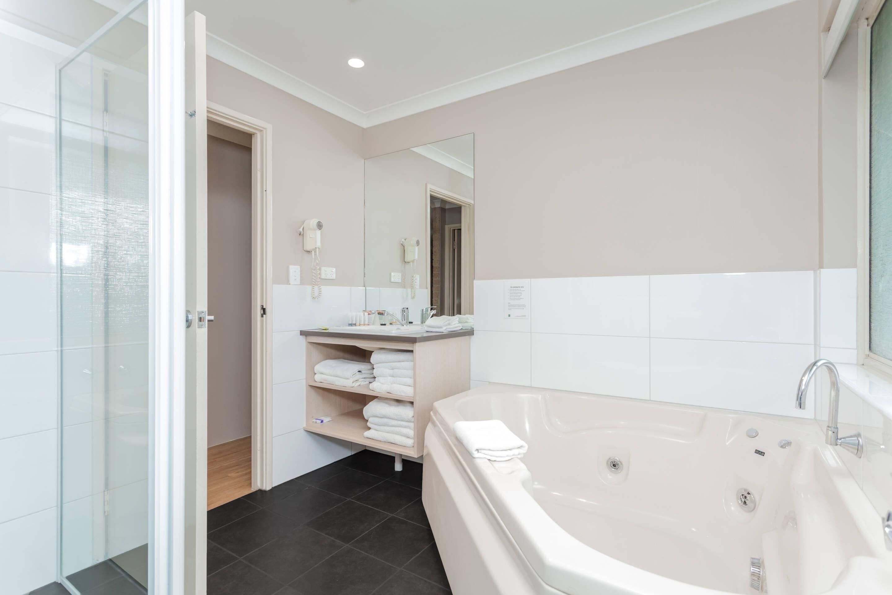 Un baño moderno con una bañera grande, una cabina de ducha con paredes de vidrio y un tocador con espejo.