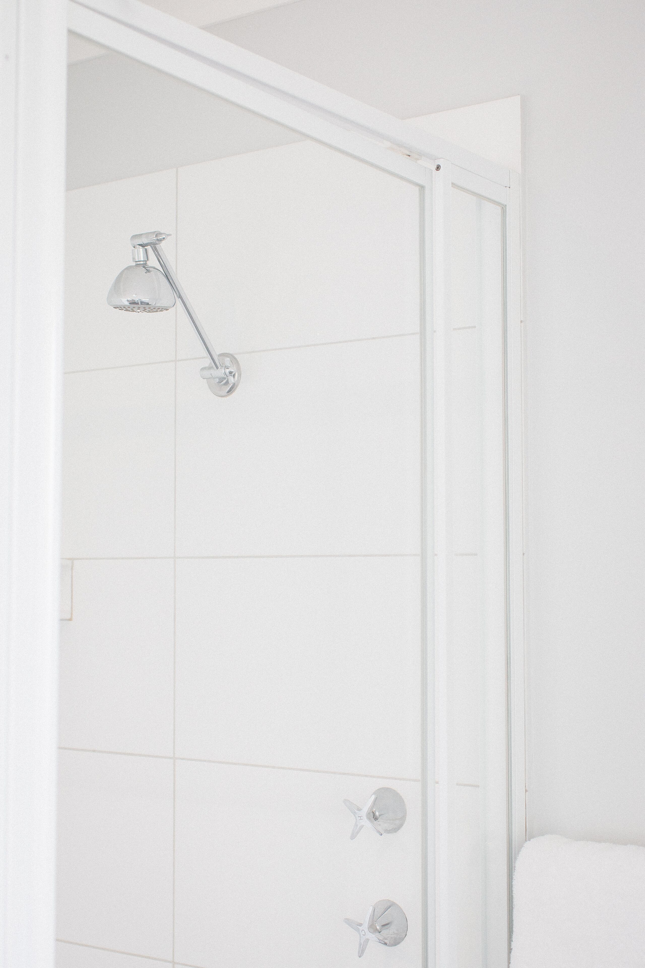 A white shower with a handheld showerhead and a glass-enclosed shower area.