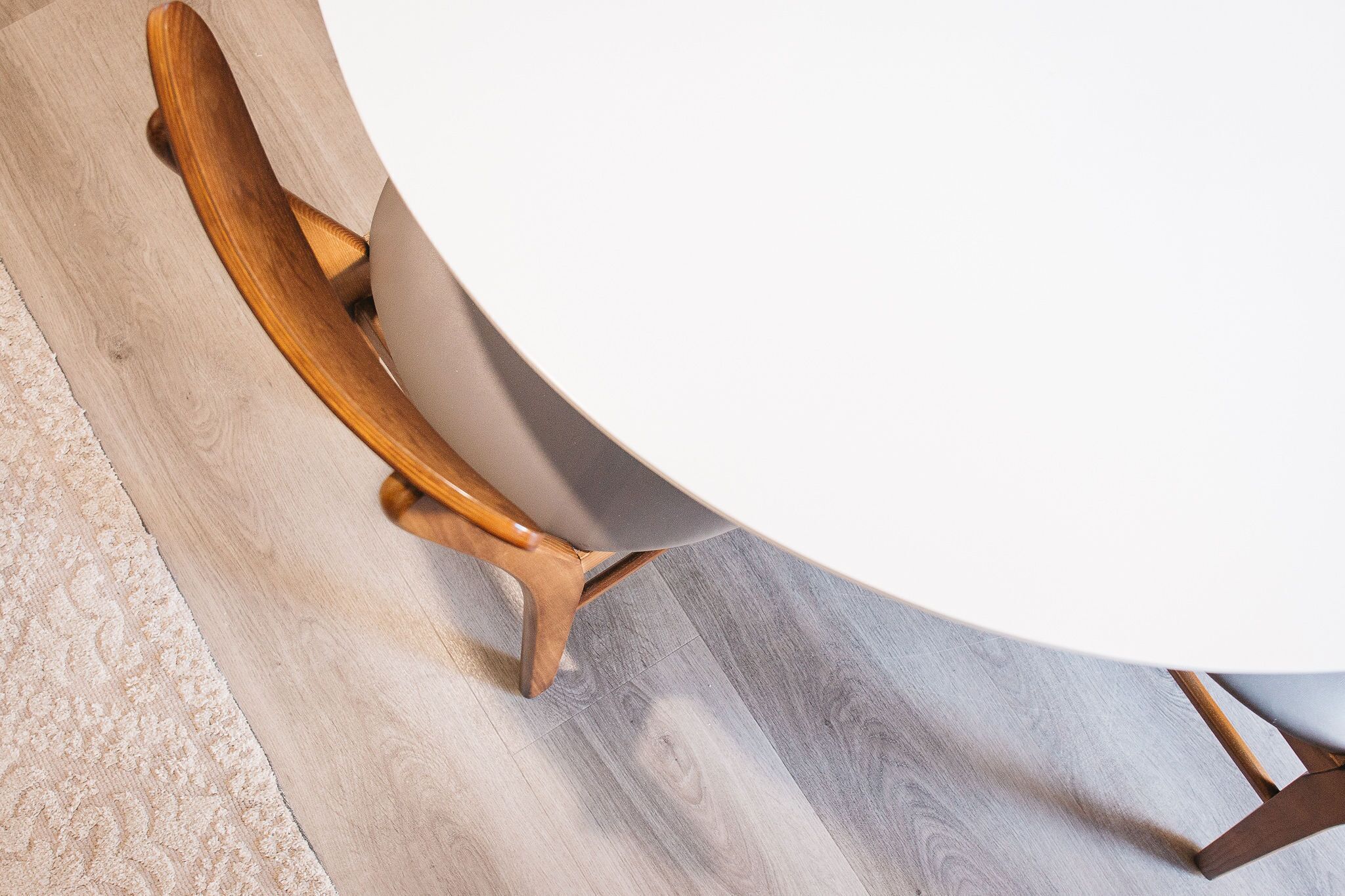 A round table with a white top and wooden legs.