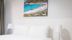 A hotel room with a bed, a bedside lamp, and a framed picture of a beach. - Quality Apartments Banksia Albany (Centennial Park)