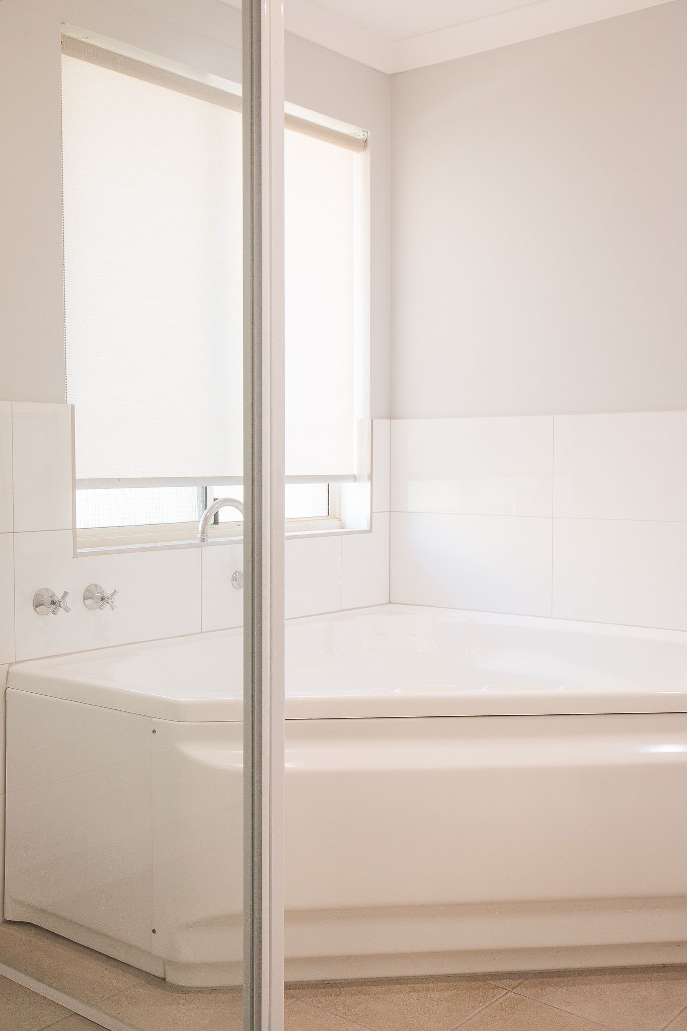Un bagno con una vasca da bagno bianca, una finestra e uno specchio.