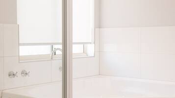 Un bagno con una vasca da bagno bianca, una finestra e uno specchio.