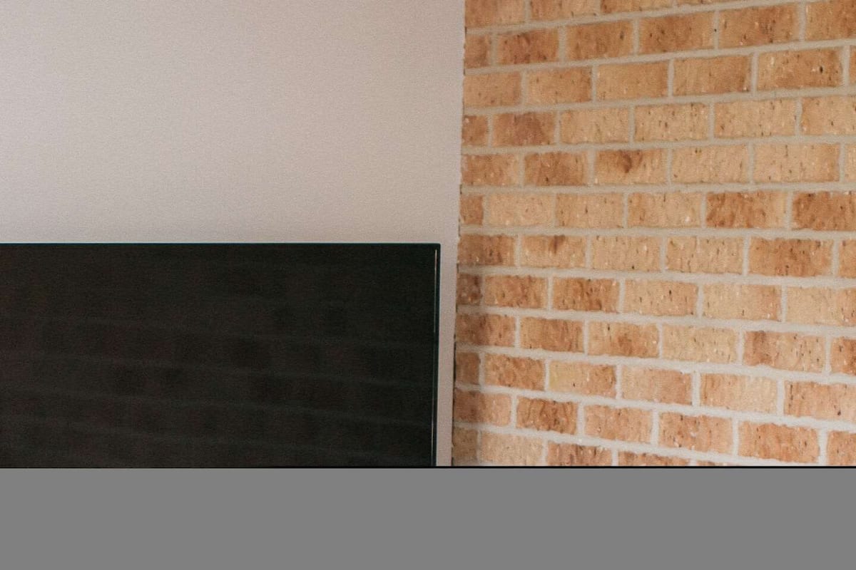 Une pièce avec un mur blanc, une cheminée noire et un mur en briques.