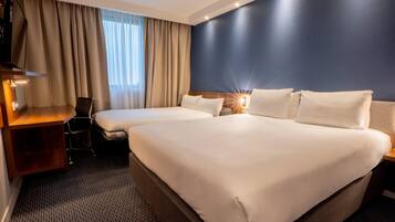 A hotel room with two beds, a desk, and a chair.