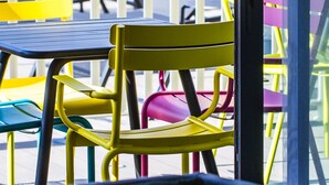 A view of a balcony with colorful chairs and tables, a railing, and a glass door. - Holiday Inn Express Dijon by IHG (Saint-Apollinaire)