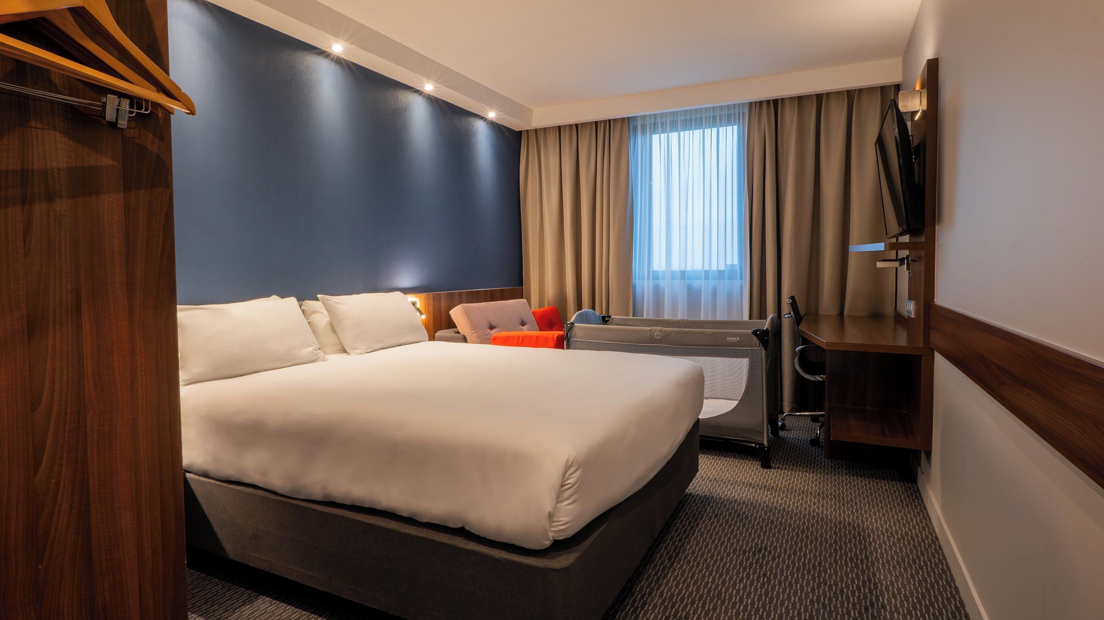 Una habitación de hotel con una cama grande, un escritorio, una silla y un televisor.