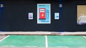 A charging station with a sign indicating it's free for clients, a parking space with a green bike lane, and a vehicle in the background. - Holiday Inn Express Dijon by IHG (Saint-Apollinaire)