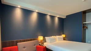 Une chambre d’hôtel avec un lit, un canapé et deux lampes de chevet.