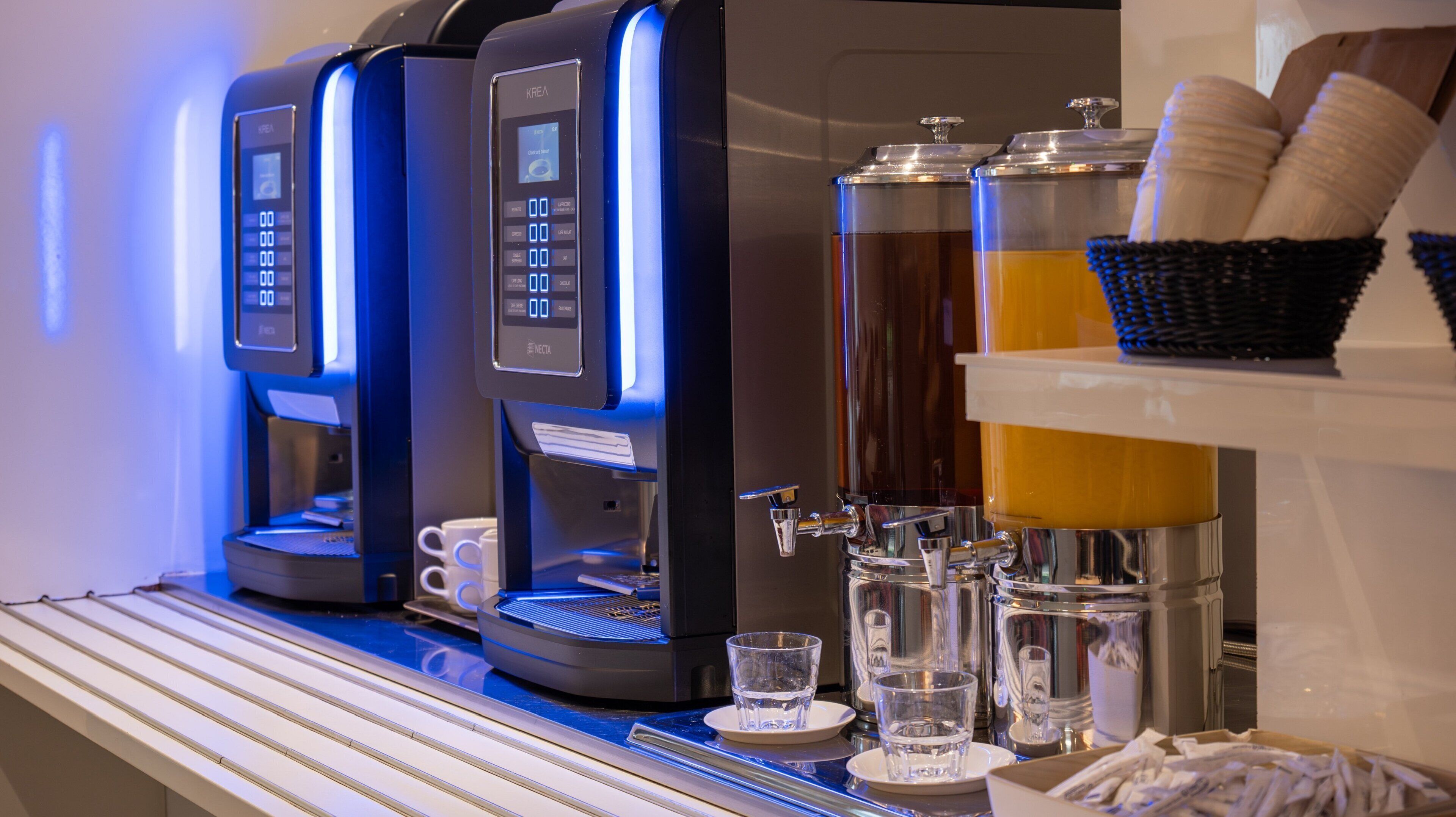 A coffee machine with a digital display, a water dispenser, and a beverage dispenser with cups and glasses.