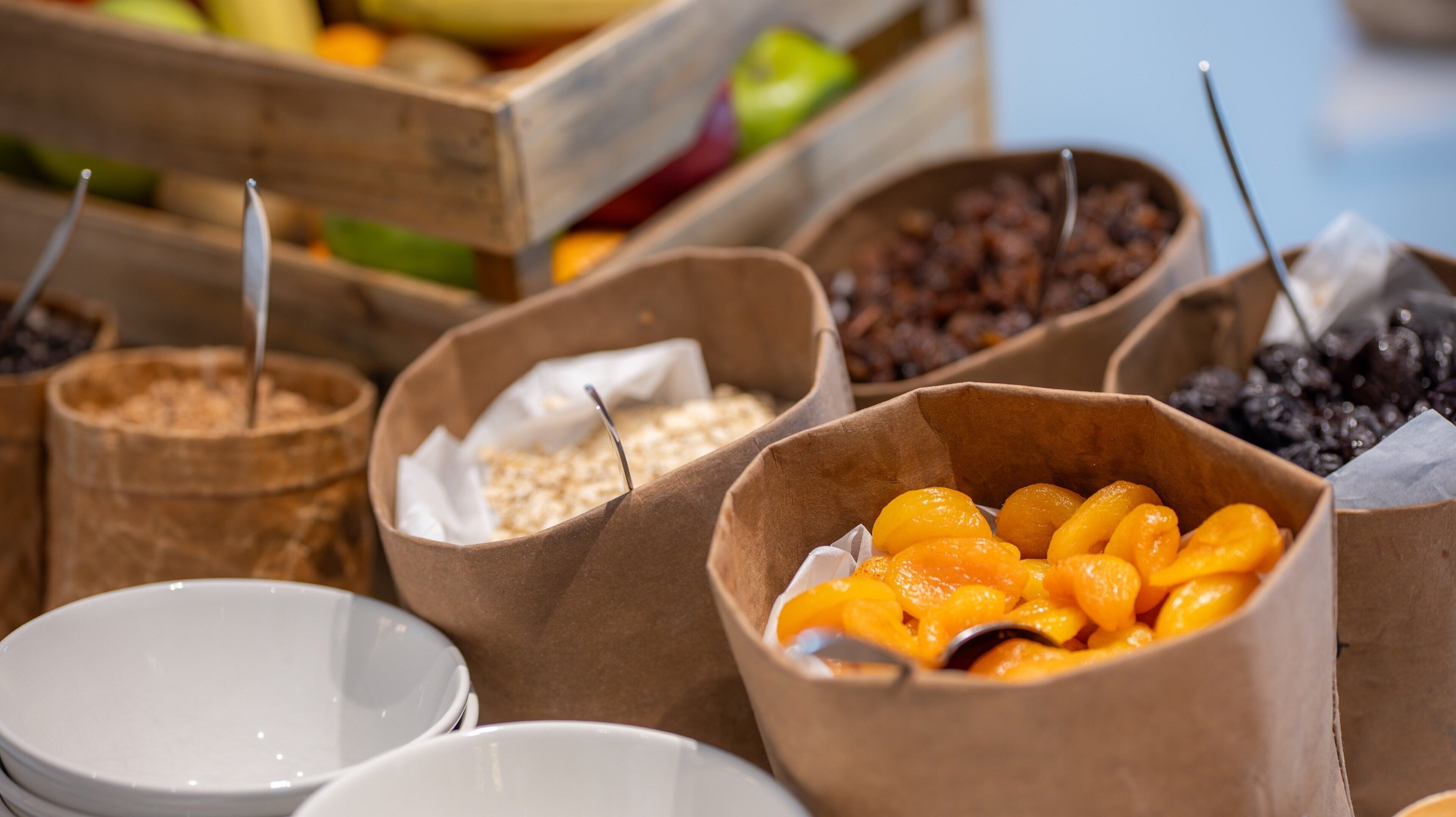 A variety of food items in paper containers, including dried fruits and nuts.