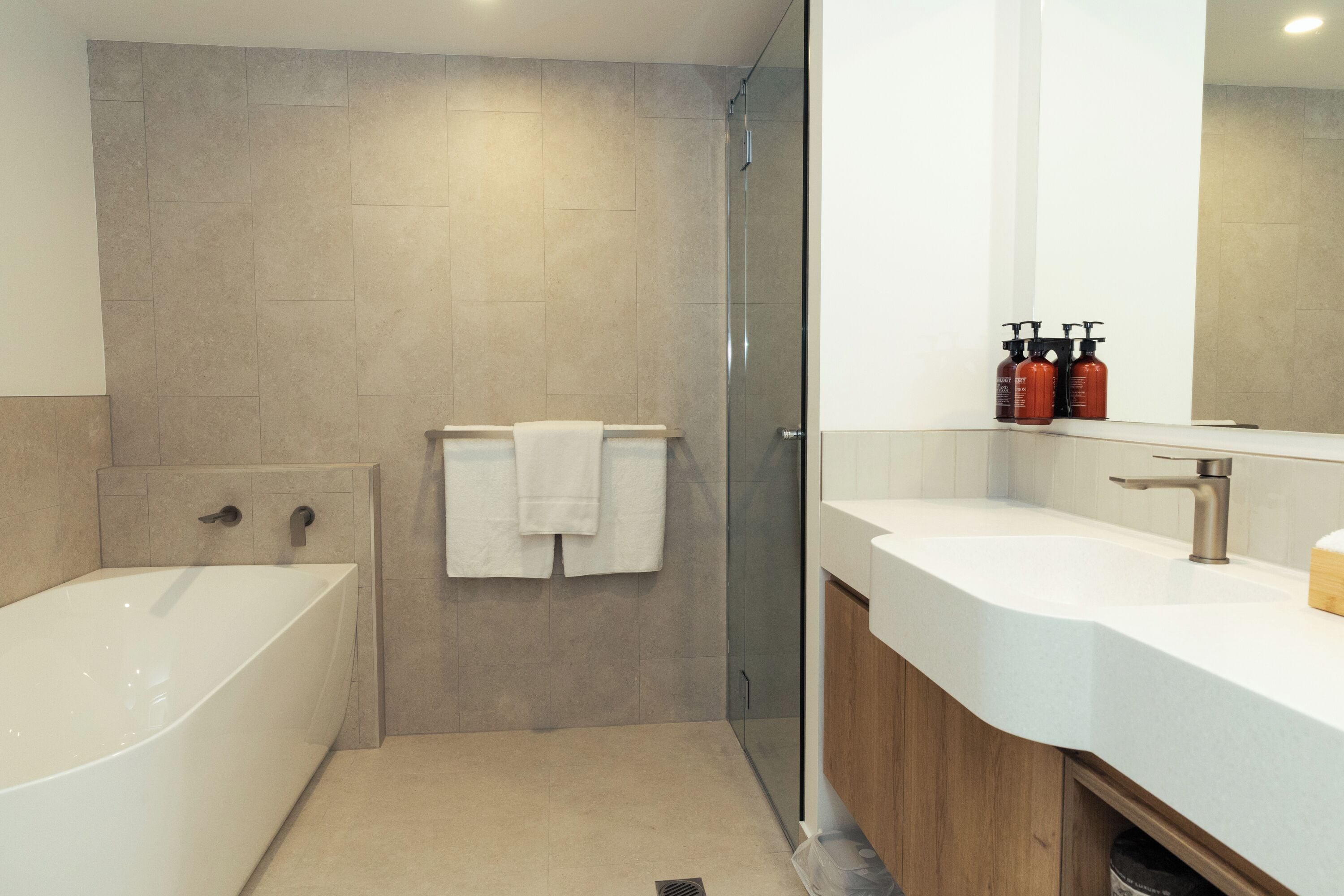 A modern bathroom with a freestanding bathtub, a glass-enclosed shower, and a vanity with a large mirror.