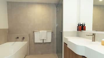 A modern bathroom with a freestanding bathtub, a glass-enclosed shower, and a vanity with a large mirror.