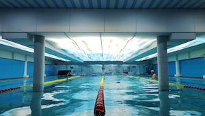 An indoor swimming pool with lanes, pillars, and a ceiling with lights. - Beijing Olympic Park Boutique Hotel (Beijing)