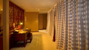 A hotel room with a traditional Chinese-style partition, a wooden desk with a lamp, and a checkered curtain. - Beijing Olympic Park Boutique Hotel (Beijing)