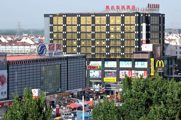 A modern hotel with a large glass facade, multiple signage, and a busy street scene in the foreground.