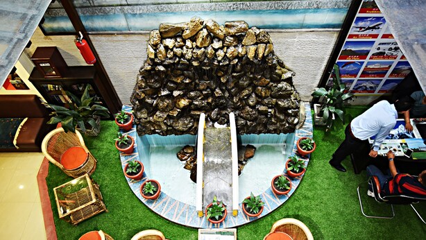 A lobby with a central rock formation, artificial grass, wicker furniture, and potted plants. - The Hotel Pleasure Home Inn (Kathmandu)