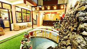 A hotel lobby with a reception desk, a small indoor pool, and several potted plants. - The Hotel Pleasure Home Inn (Kathmandu)