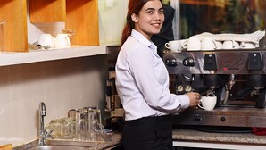 A coffee shop interior with a coffee machine, cups, and a shelf with jars. - The Hotel Pleasure Home Inn (Kathmandu)