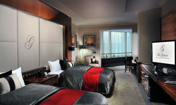 A hotel room with two beds, a desk, a television, and a window with curtains. - Sun City Hotel - The Gabriel (Cairo)