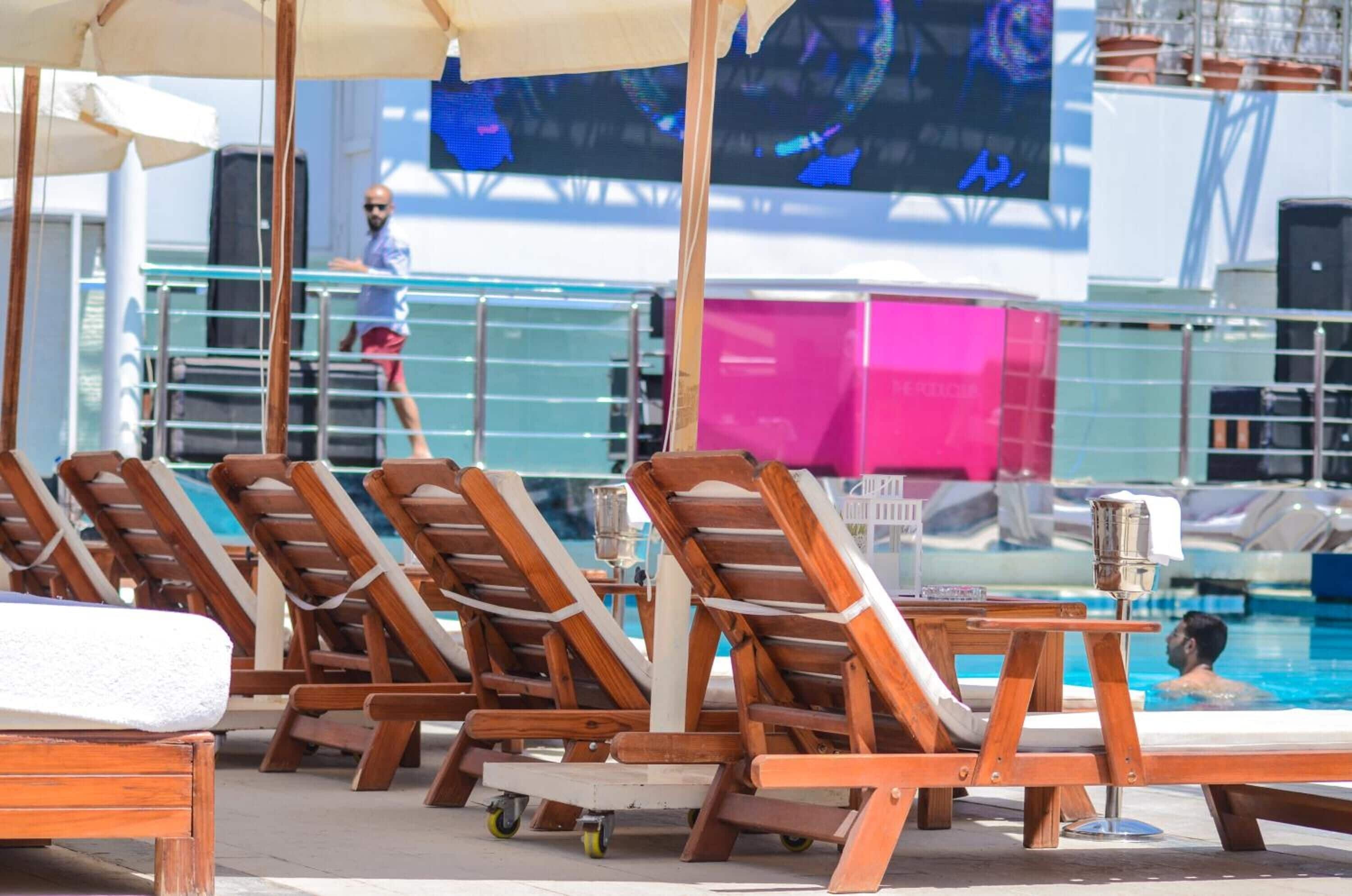 A poolside area with wooden lounge chairs and a pool.