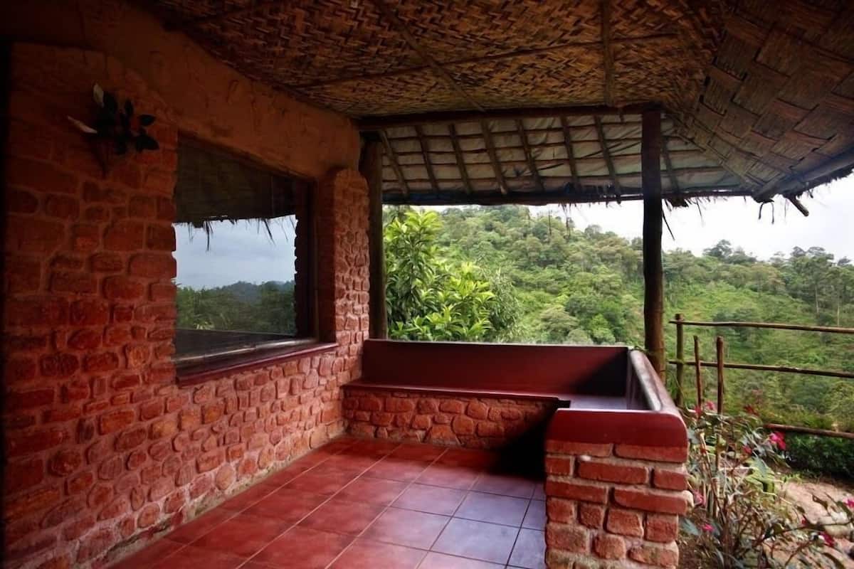 A room with a brick wall, a window, and a view of a lush green landscape.