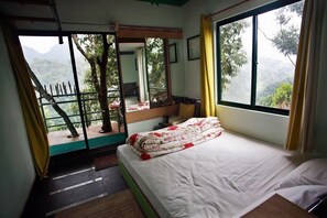 A bedroom with a bed, a window with a view of the outdoors, a balcony, and a door leading to another room. - Wild Elephant Eco-Friendly Resort (Devikolam)