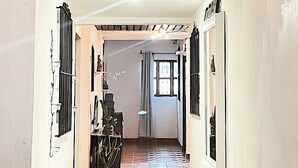 Un couloir avec un sol carrelé, un coin repas avec une table et des chaises, et une fenêtre avec des rideaux.