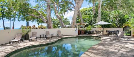 Een buitenzwembad, parasols bij het zwembad en ligstoelen