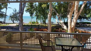 A covered outdoor seating area with a view of the beach and ocean. - On Palm Cove Beachfront Apartments (Palm Cove)