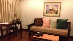 A living room with a sofa, a coffee table, a dining table with chairs, and a framed picture on the wall. - Cucumber Inn (Pattaya)