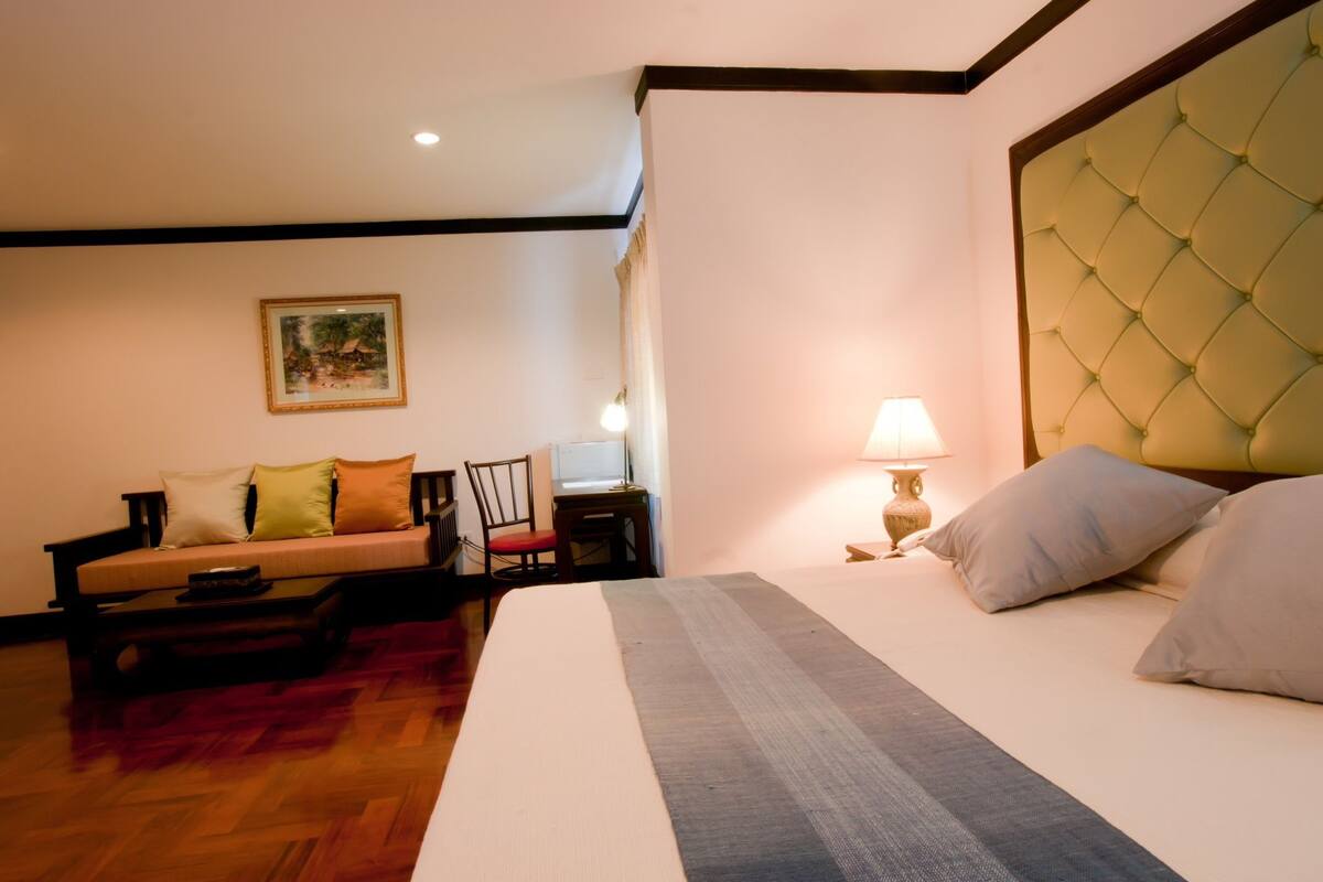 Una habitación de hotel con cama, sofá, escritorio y lámpara.