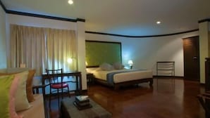 A hotel room with a bed, a desk, a chair, and a small table. - Cucumber Inn (Pattaya)