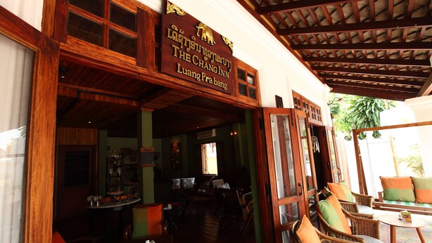 Una estructura de madera tradicional con un letrero que indica 'The Chang Inn Luang Prabang'.