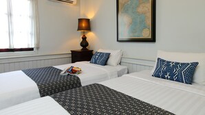 Habitación de hotel con dos camas, un mapa en la pared, una lámpara y una ventana con cortinas.