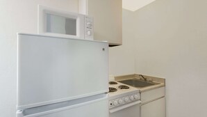 Een kleine keuken met een witte koelkast, magnetron en fornuis.