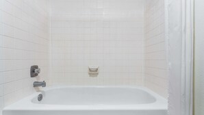 Een badkamer met een witte badkuip, een handdoekhouder en een zeepbakje aan de muur.