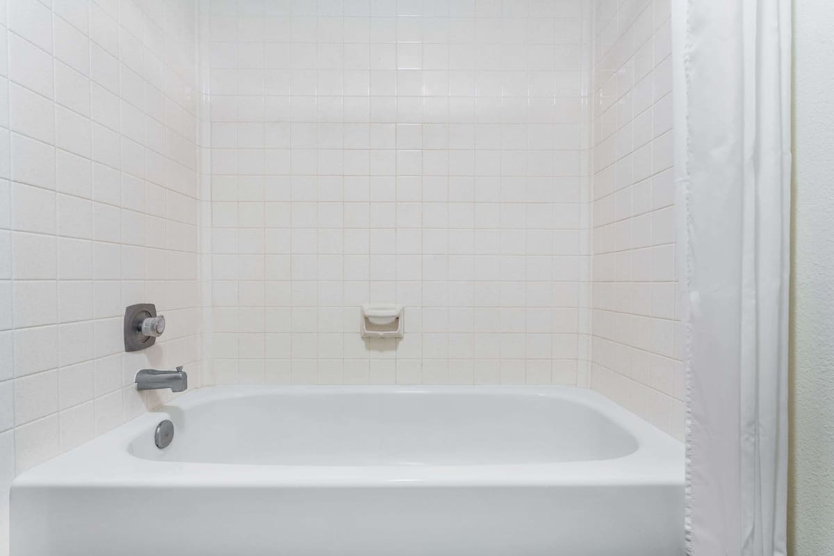 A bathroom with a white bathtub, a towel rack, and a soap dish on the wall.