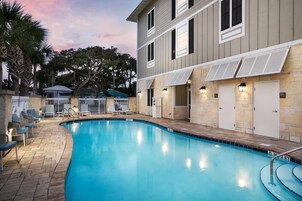 Una piscina al aire libre, sombrillas, sillones reclinables de piscina