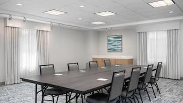 A conference room with a long table, chairs, a whiteboard, and a painting on the wall.