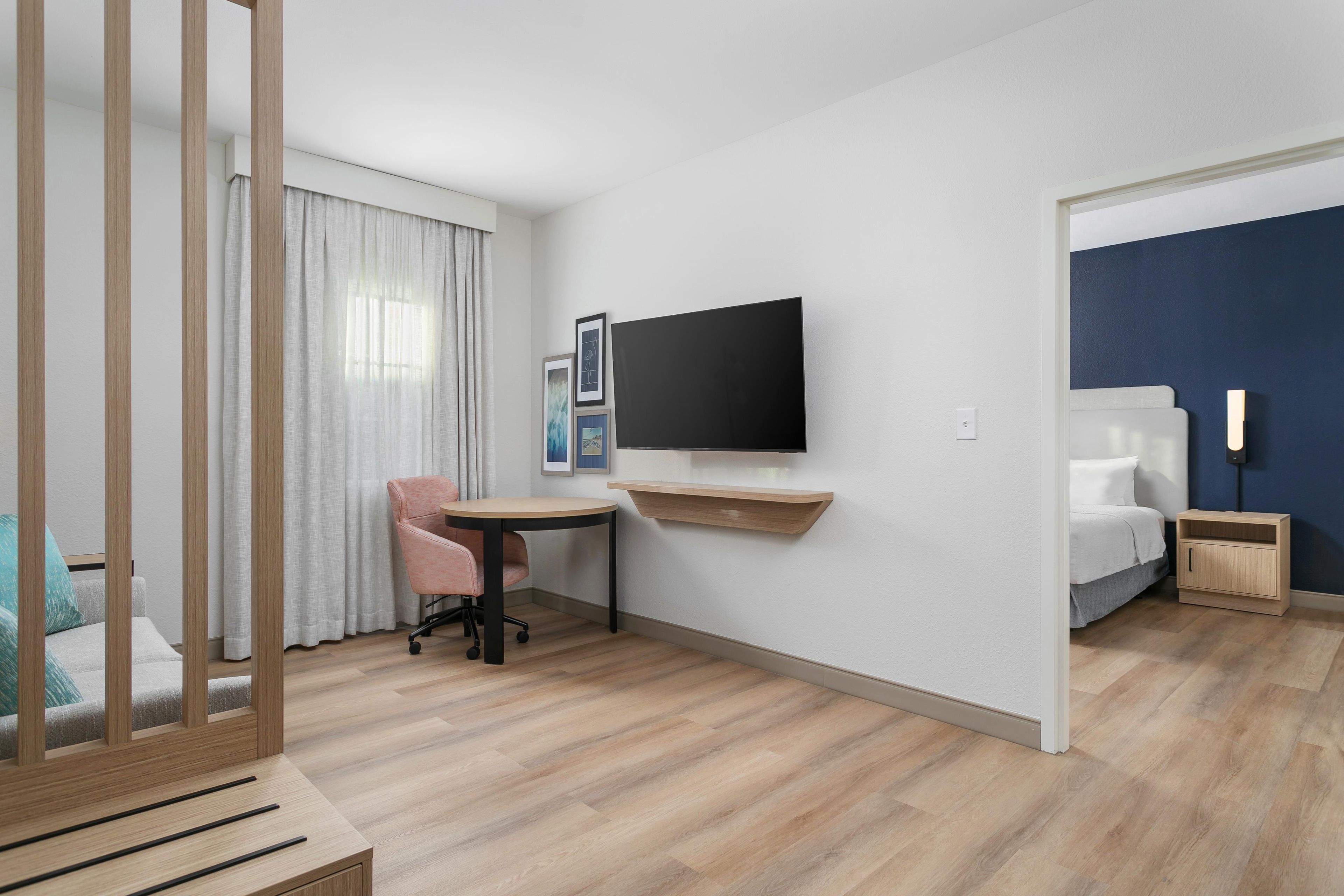 Una habitación de hotel con escritorio, silla, cama, televisor y mesita de noche.