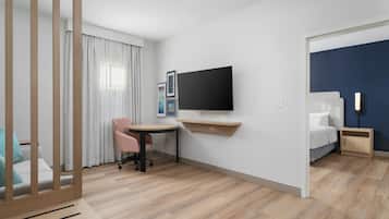 Una habitación de hotel con escritorio, silla, cama, televisor y mesita de noche.